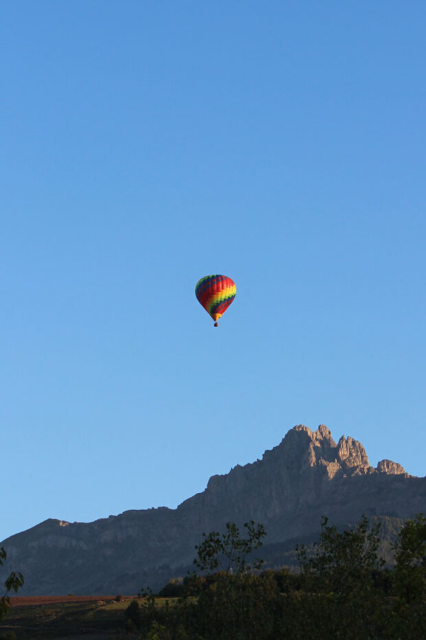 Ein Heißluftballon vor blauem Himmel und Alpen Panorama